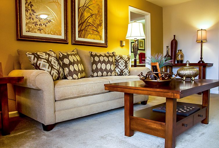 A cozy living room with a beige sofa, patterned cushions, and wooden coffee table.