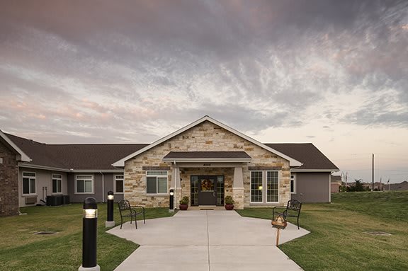 A building with a stone facade and a welcoming entrance under a cloudy sky.