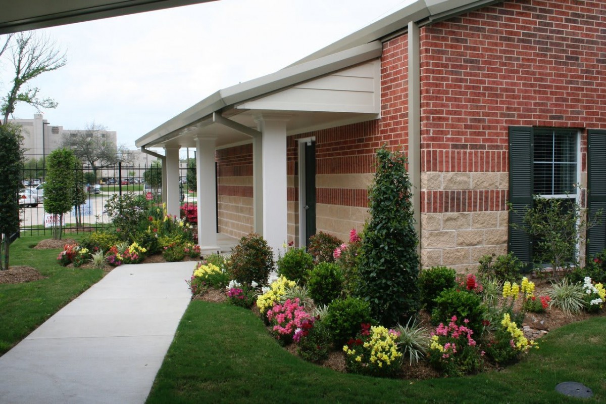 A landscaped area with flowers and bushes alongside a brick building.