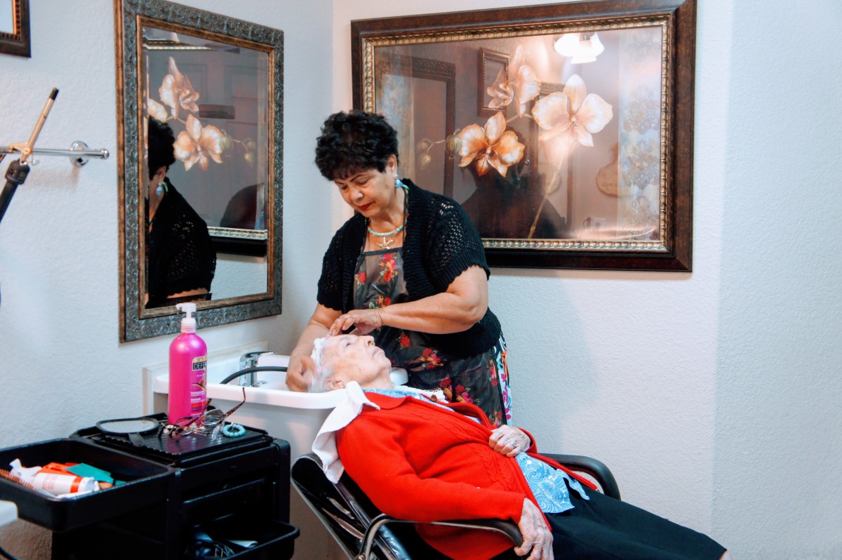 A hairstylist washing an elderly woman's hair in a salon.