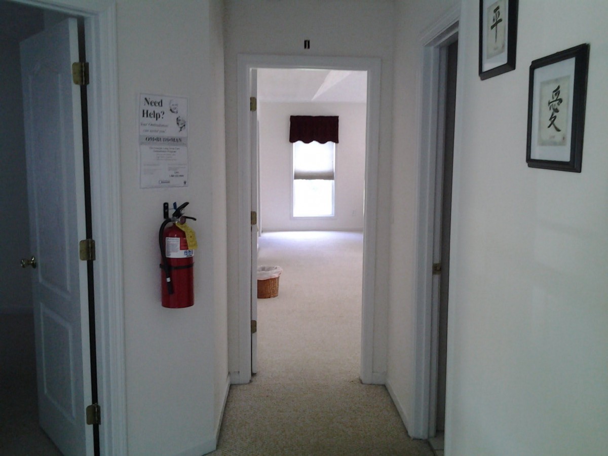 A view of a hallway with doors leading to rooms, featuring a fire extinguisher mounted on the wall.