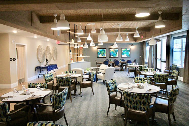 A modern restaurant dining area with elegant tables and chairs, decorated with artistic lighting and wall art.