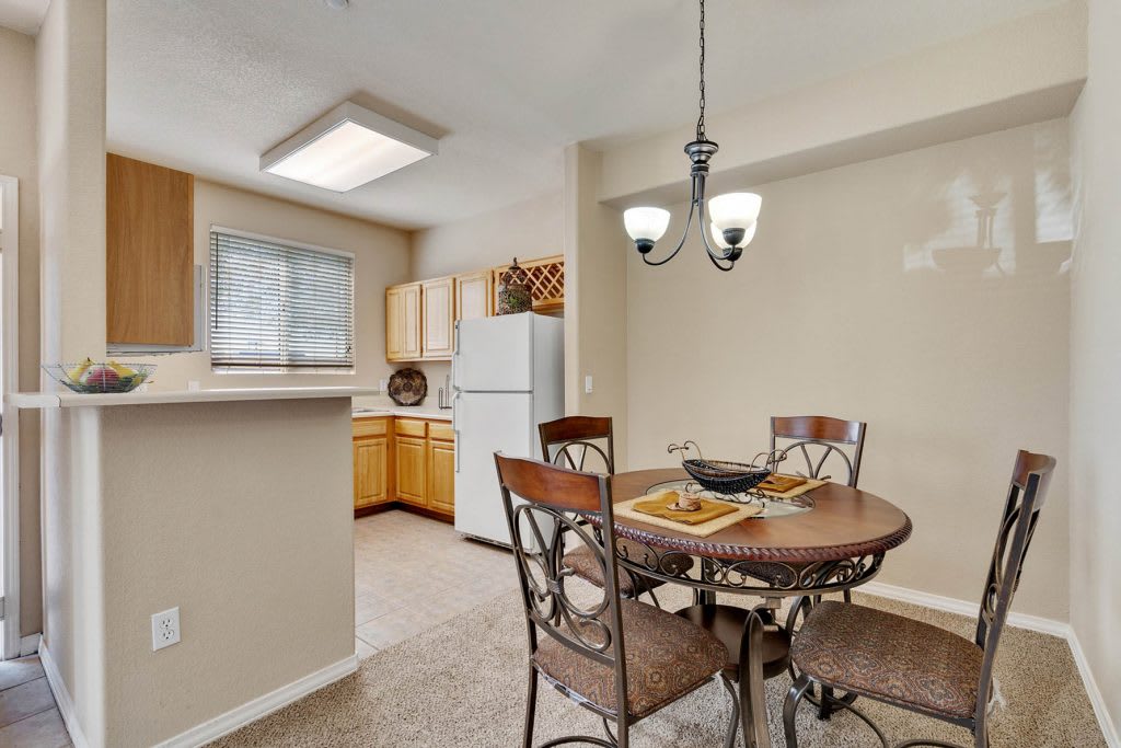 A cozy kitchen and dining area with a round table, chairs, refrigerator, and wood cabinets.