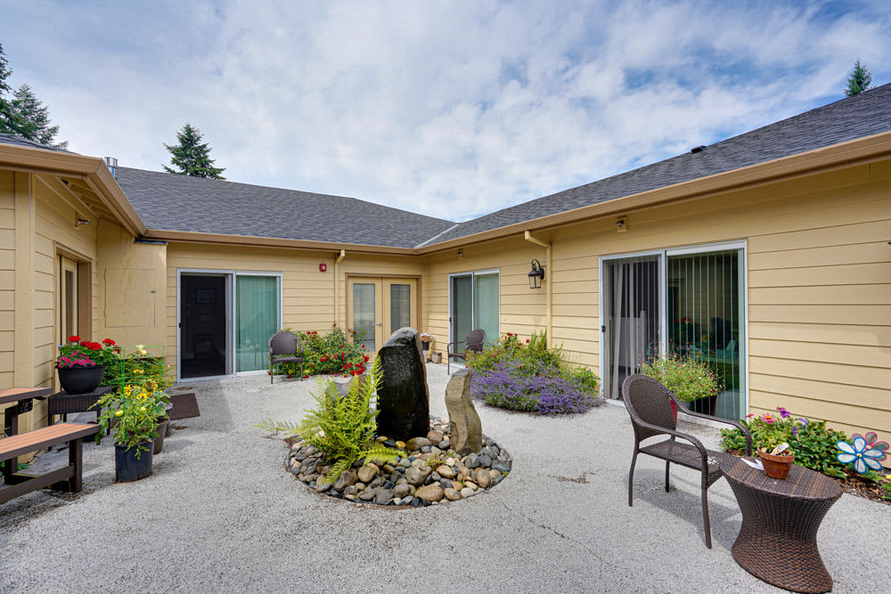 A cozy courtyard with a central fountain surrounded by plants and outdoor seating.