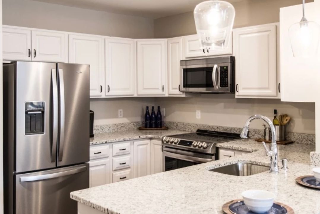 A modern kitchen with white cabinets and stainless steel appliances.