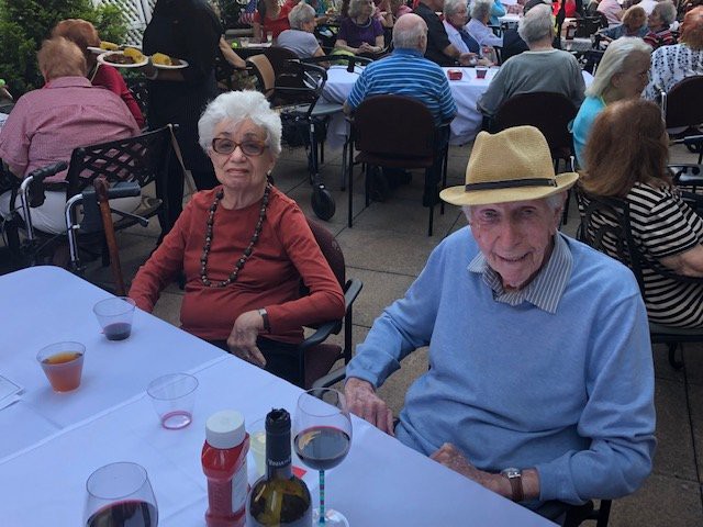 An elderly couple enjoying an outdoor meal at a restaurant.