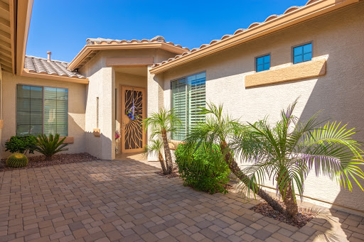 A beautifully designed entrance of a modern house with palm trees and a paved walkway.