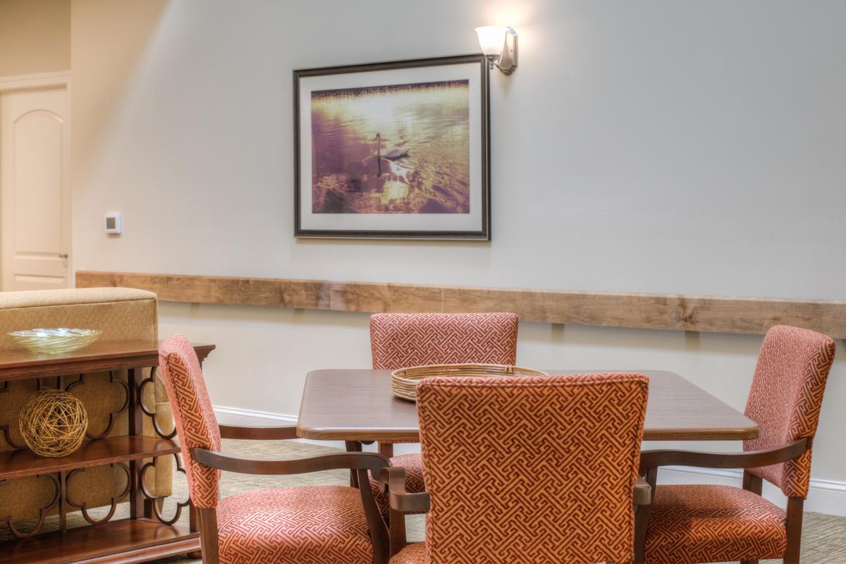 A cozy dining area with a table surrounded by chairs, adorned with wall art and soft lighting.