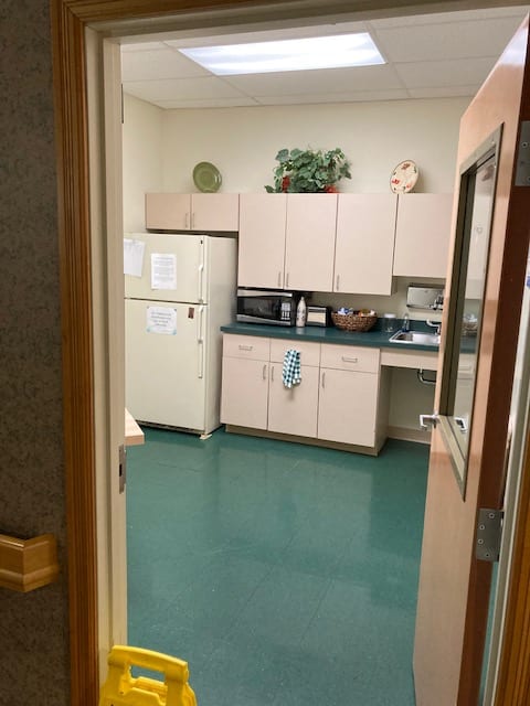 A view into a kitchen area with cabinets, appliances, and a green floor.