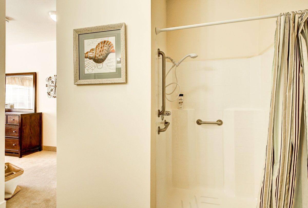 A modern bathroom featuring a walk-in shower with a glass door and framed artwork on the wall.