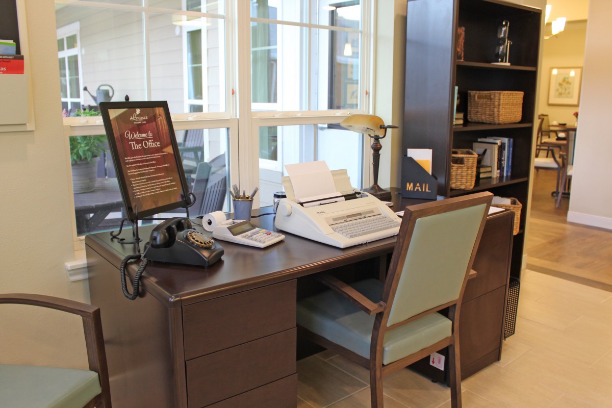 A vintage-style office setup featuring a typewriter and an old telephone on a desk.