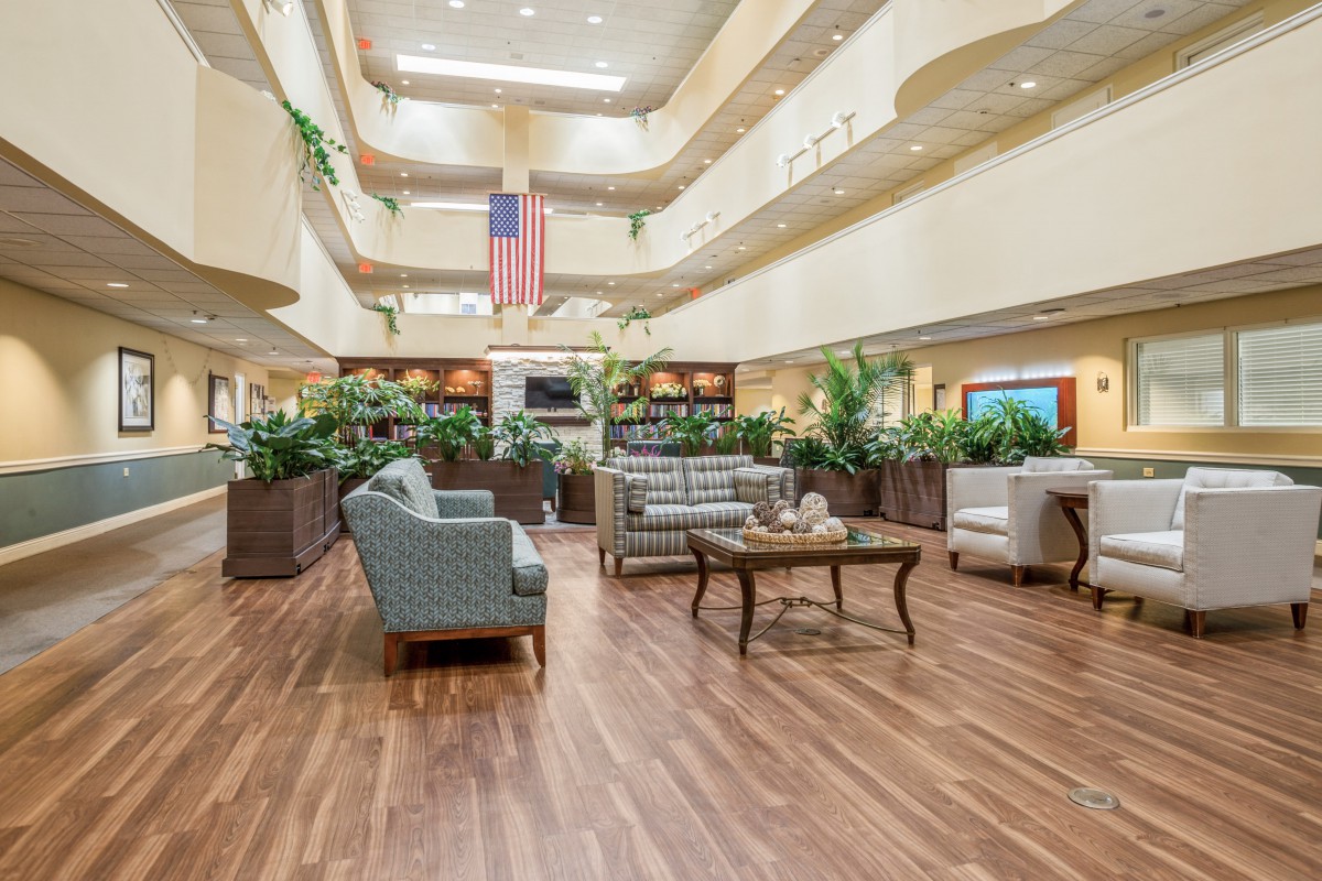 A spacious lobby with comfortable seating, plants, and a prominent flag hanging from the ceiling.