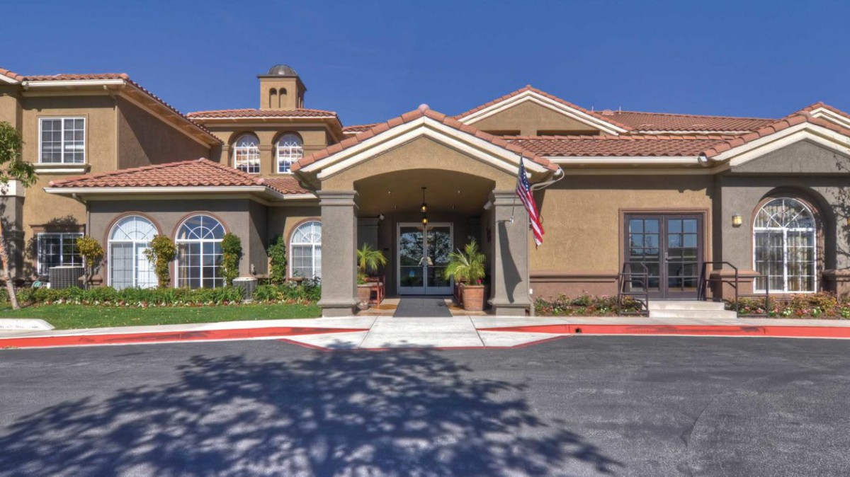 Front entrance of a residential building with landscaping and an American flag.