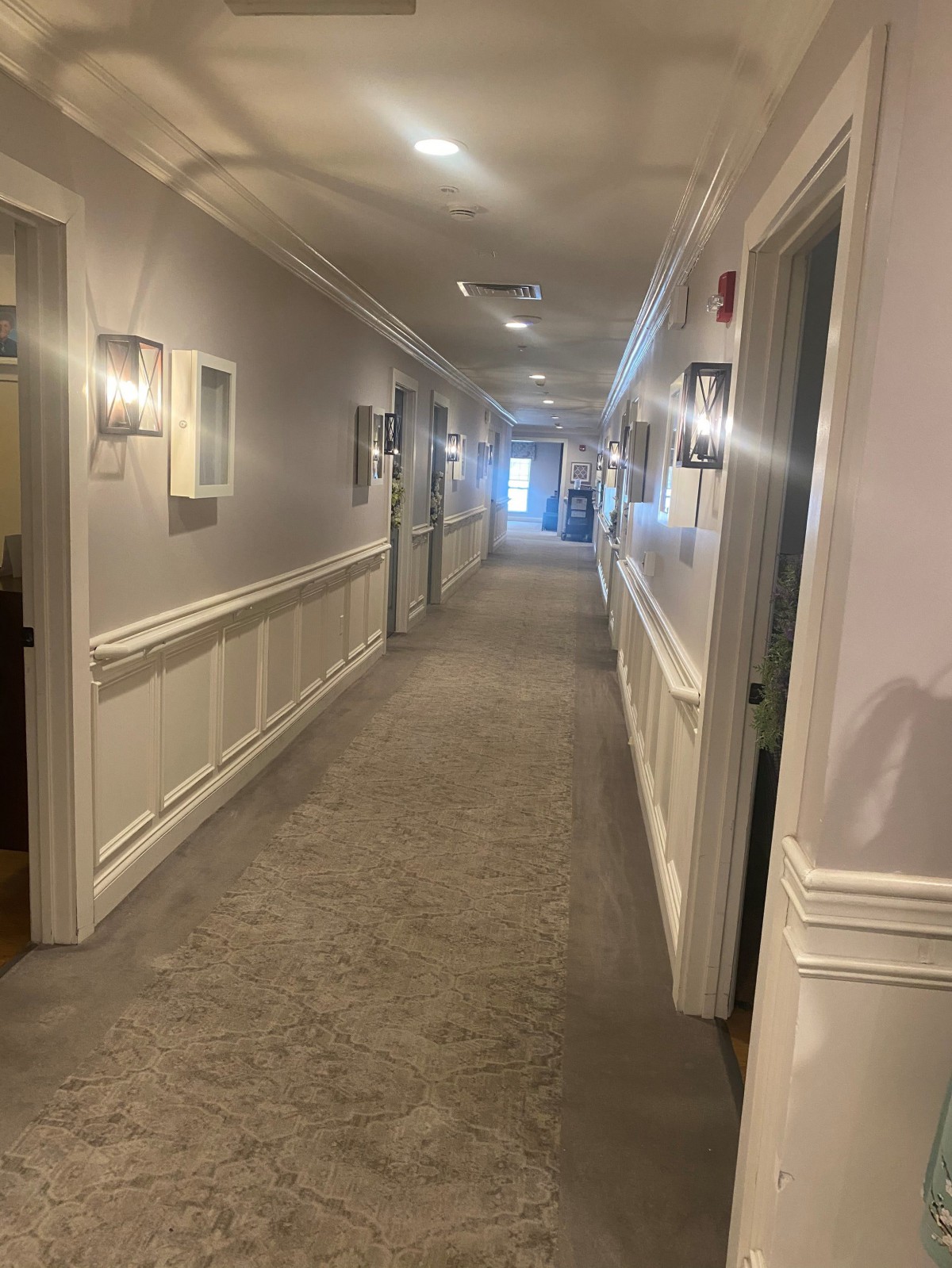 A well-lit hallway with several doors and carpeted floor.