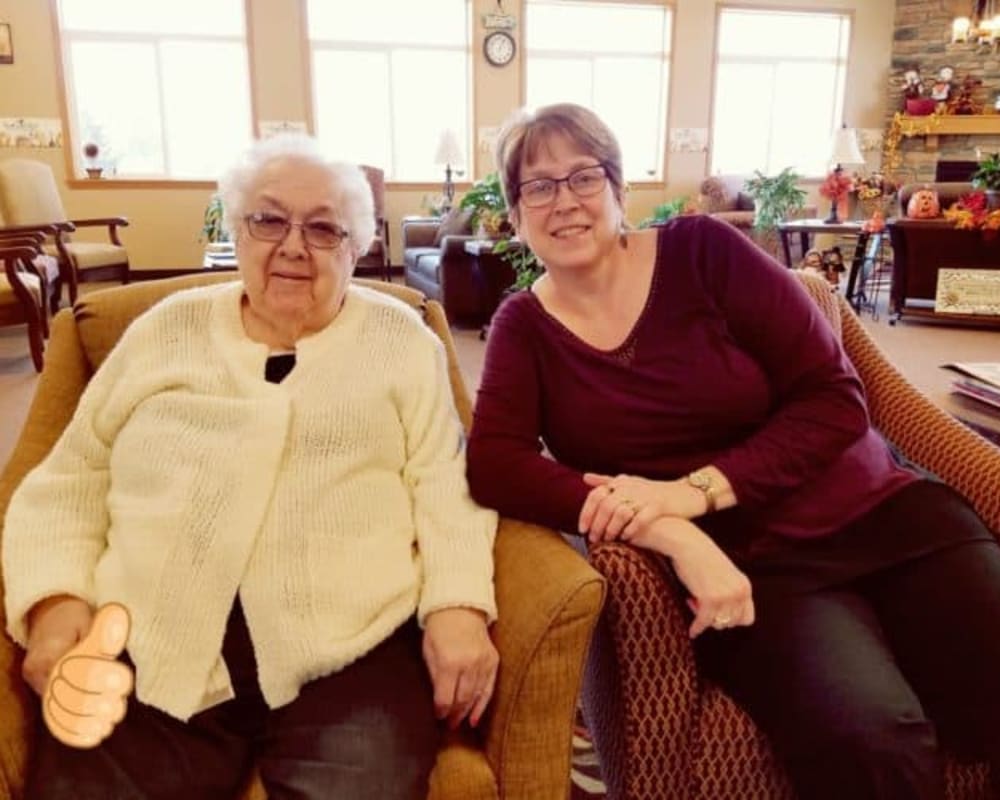 Two women sitting together on a sofa in a comfortable living room setting.