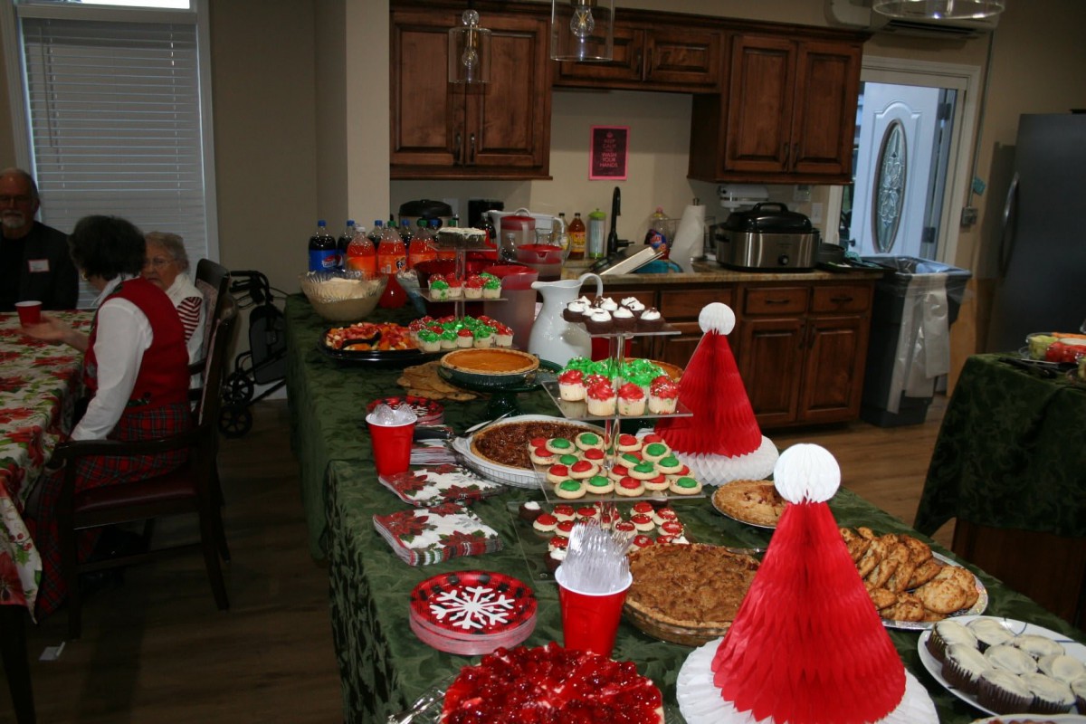 A kitchen table filled with Christmas-themed food and decorations for a holiday party.