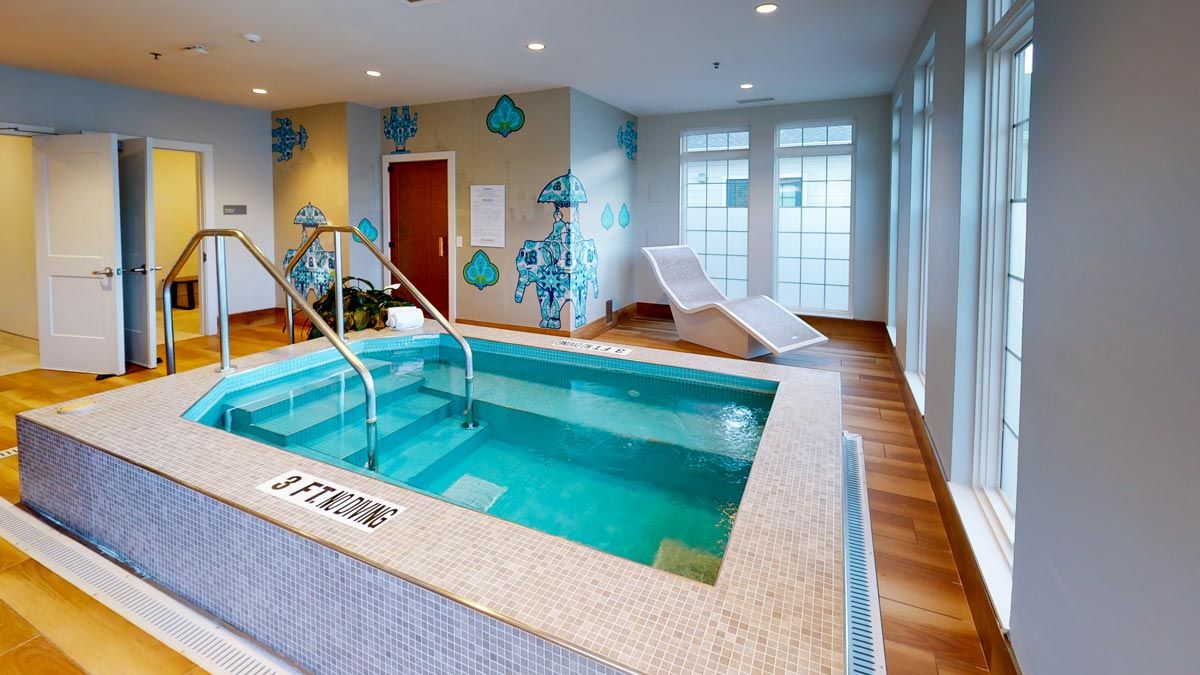 A modern indoor spa area with a small pool and relaxation chairs.