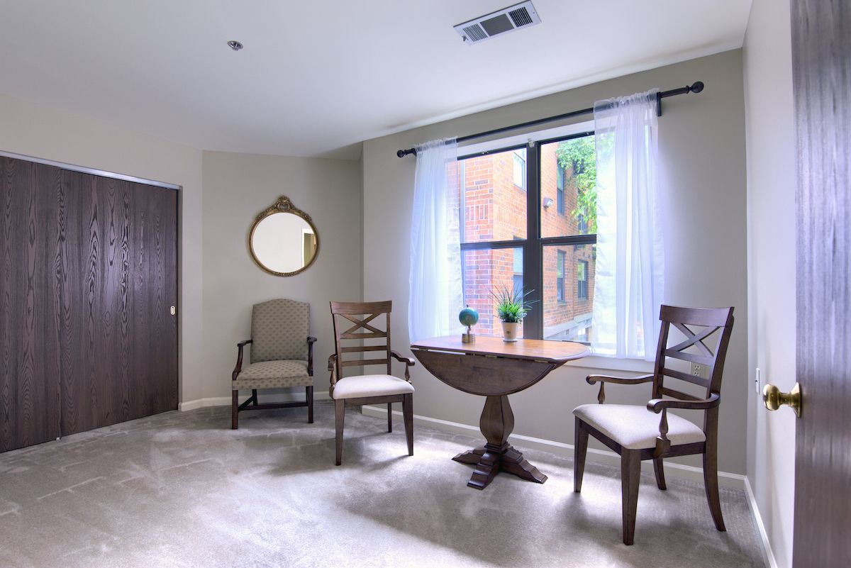 A cozy living space with a small round table, chairs, and a window letting in natural light.