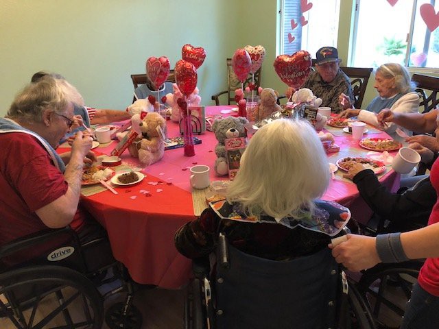 A group of seniors enjoying a festive gathering with heart-themed decorations and balloons.