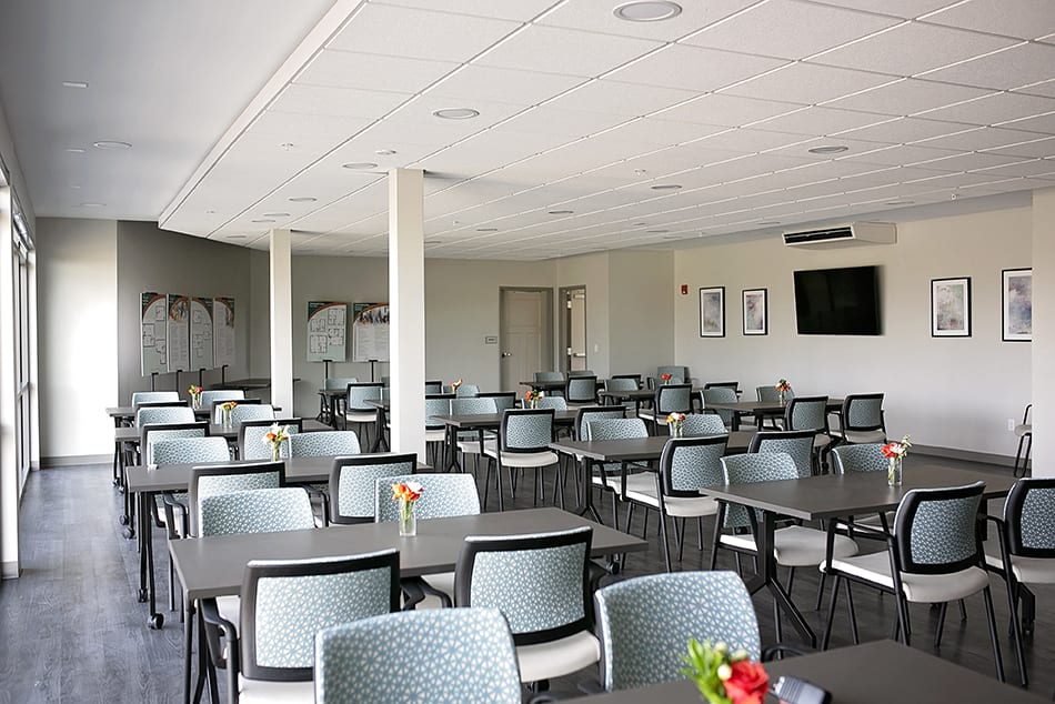 An empty conference room with tables and chairs arranged for a meeting.