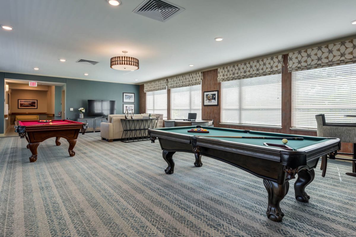 A spacious game room featuring multiple pool tables and a comfortable seating area.