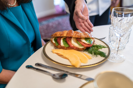 A beautifully arranged croissant sandwich with fresh vegetables and cheese on a plate, ready to be enjoyed.