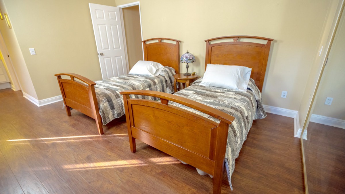 A cozy bedroom featuring two twin beds with wooden frames and matching bedding.