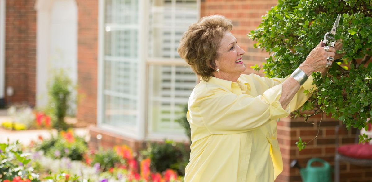A woman happily tending to her garden, surrounded by colorful flowers.