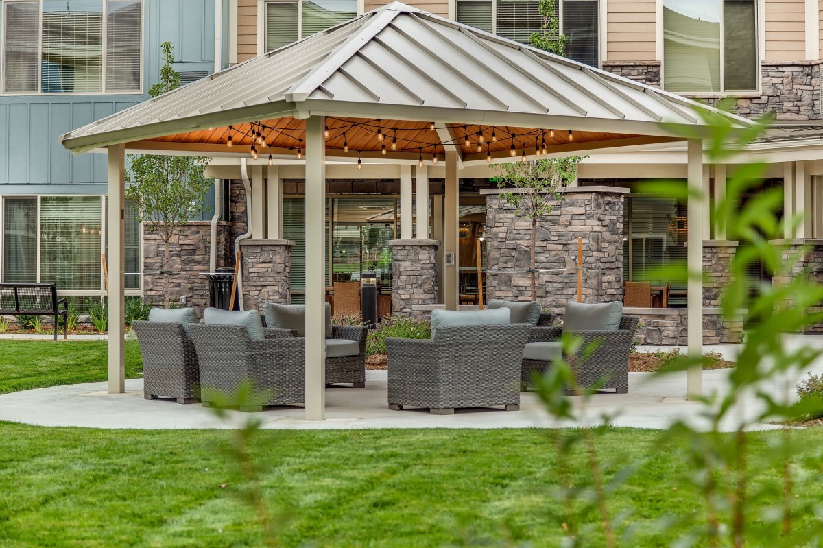 A cozy outdoor gazebo with comfortable seating surrounded by a well-maintained lawn.