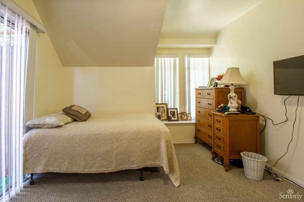 A cozy bedroom with a bed and a dresser adorned with decorations.