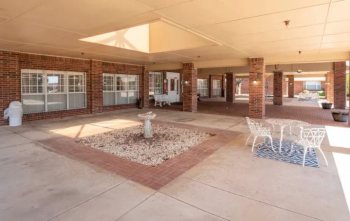 A spacious courtyard with a central fountain and brick surrounding, featuring multiple windows.