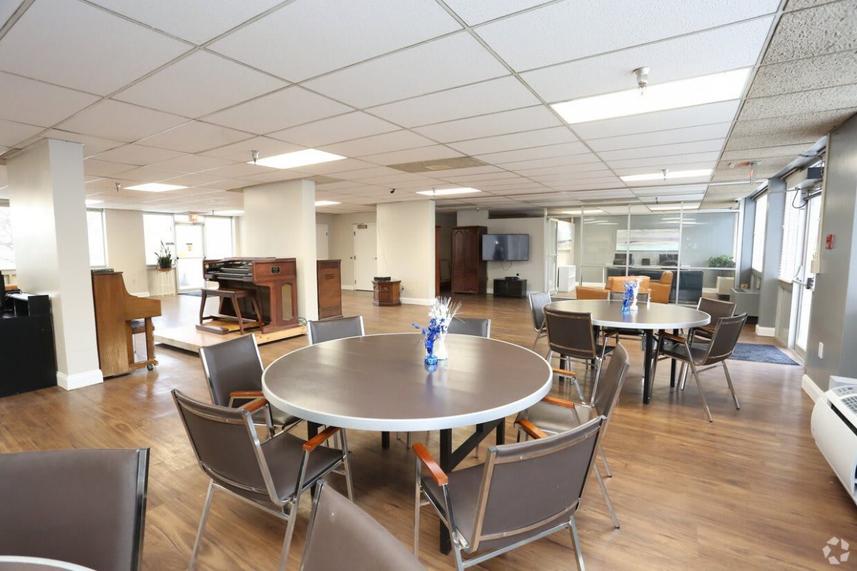 An empty office break room with tables and chairs arranged for employees.