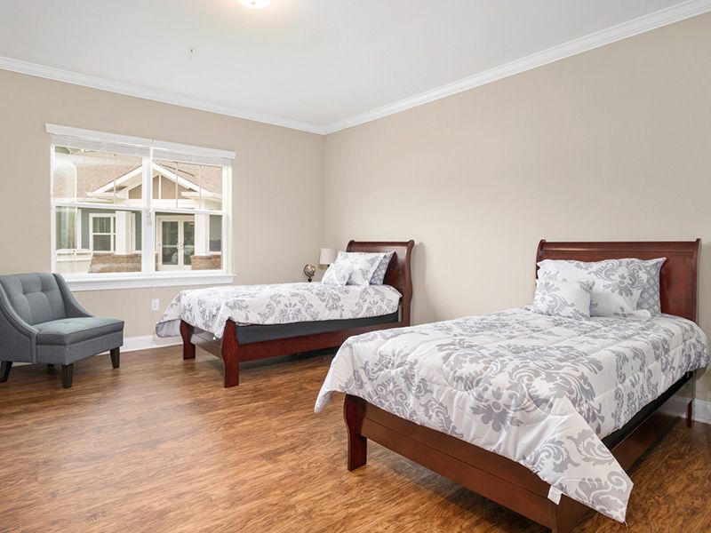 A clean and bright bedroom featuring two twin beds with wooden frames and a large window.