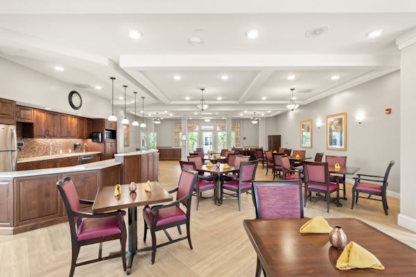 A spacious and modern dining area with elegant tables and chairs, featuring warm lighting and a welcoming atmosphere.