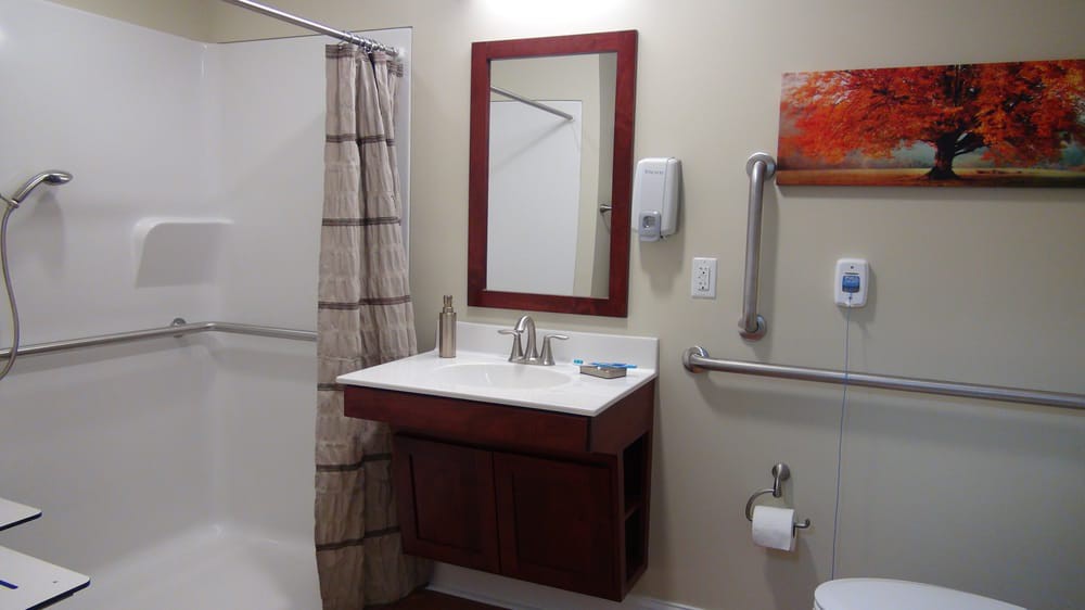 A modern bathroom with a sink, mirror, shower, and accessibility features.