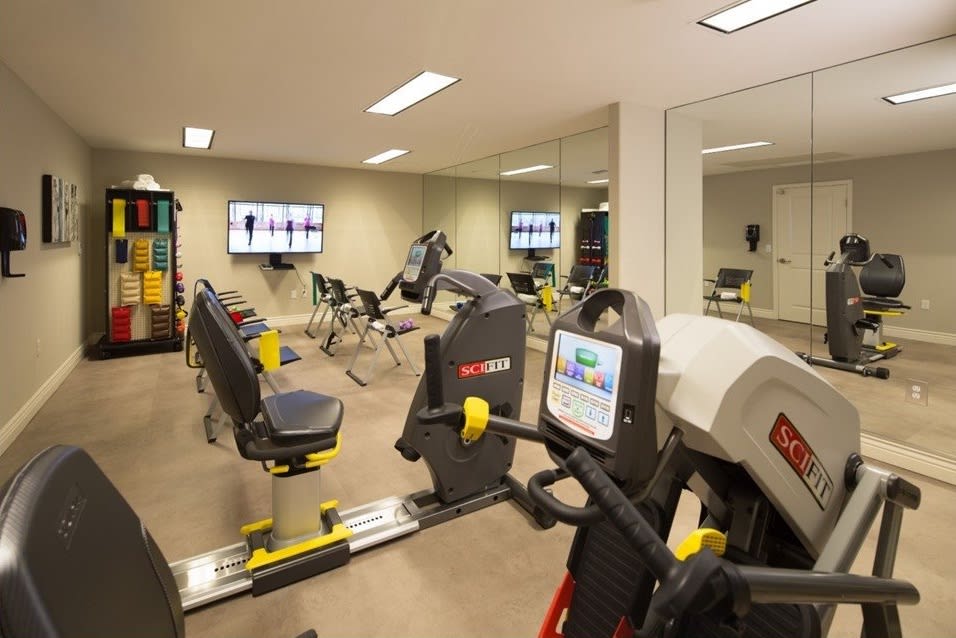 A well-equipped gym with various exercise machines and mirrors.