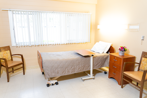 A bright and tidy hospital room featuring a bed with a bedside table.