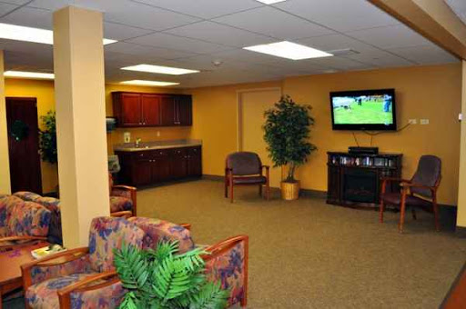 A cozy waiting area with comfortable seating, a TV, and decorative plants.