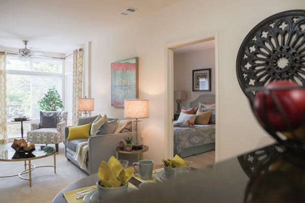 A cozy and modern living room with stylish furnishings and decor, leading into a neatly arranged bedroom.