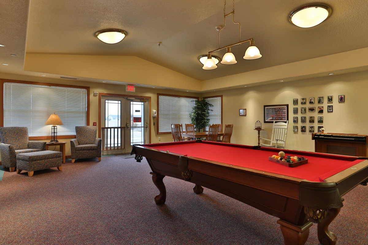 A cozy game room featuring a red pool table and comfortable seating.