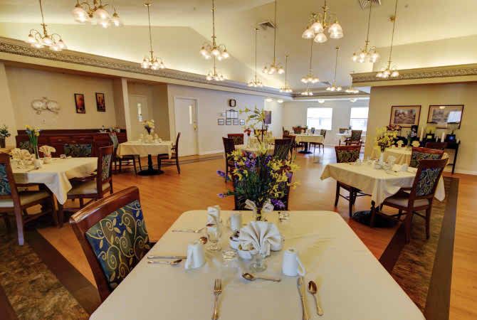A spacious dining room with elegant table settings and decorative lighting.