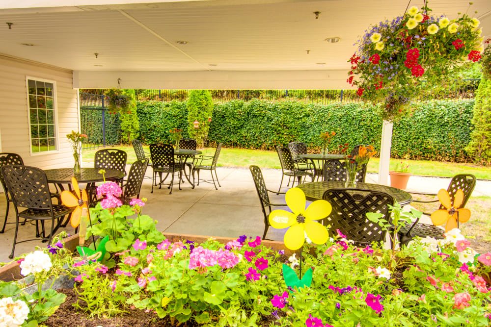 A charming outdoor patio area with tables and chairs surrounded by vibrant flowers and greenery.