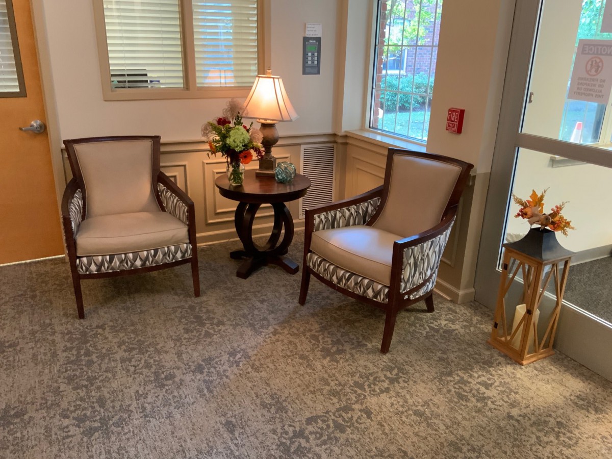 A cozy lobby area with two upholstered chairs, a wooden side table, and ambient lighting.