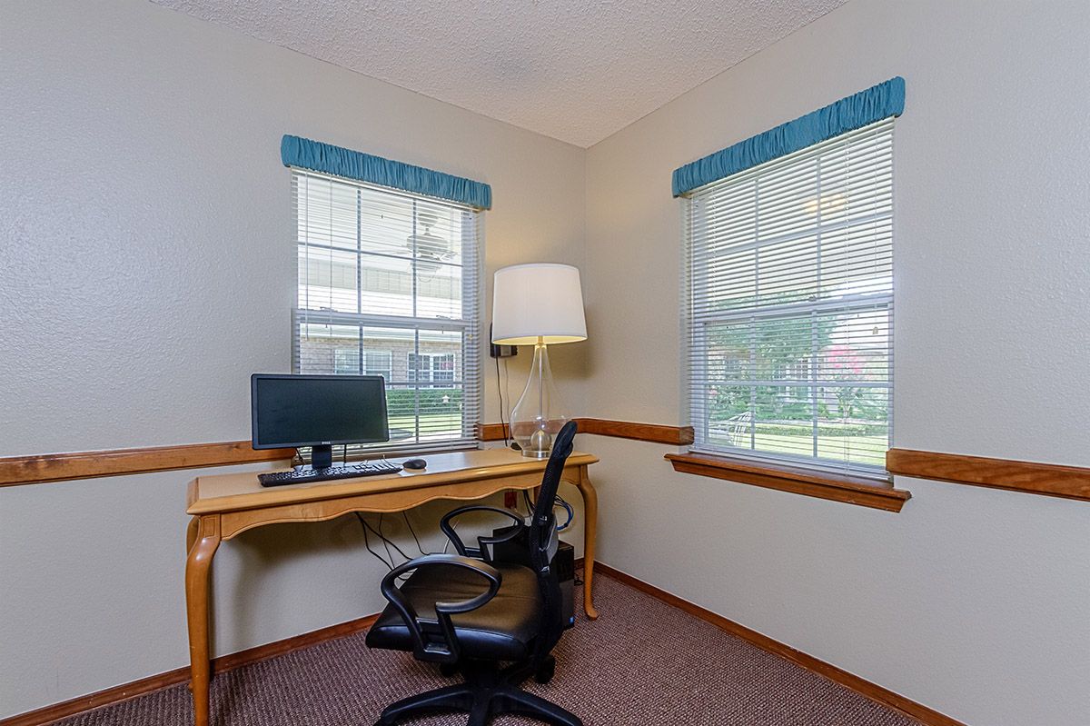 A cozy home office setup with a desk, chair, and computer by the window.