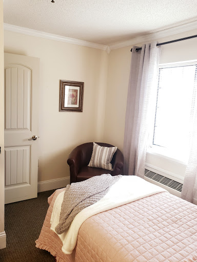 A cozy and well-lit bedroom featuring a comfortable bed, a stylish chair, and decorative artwork.