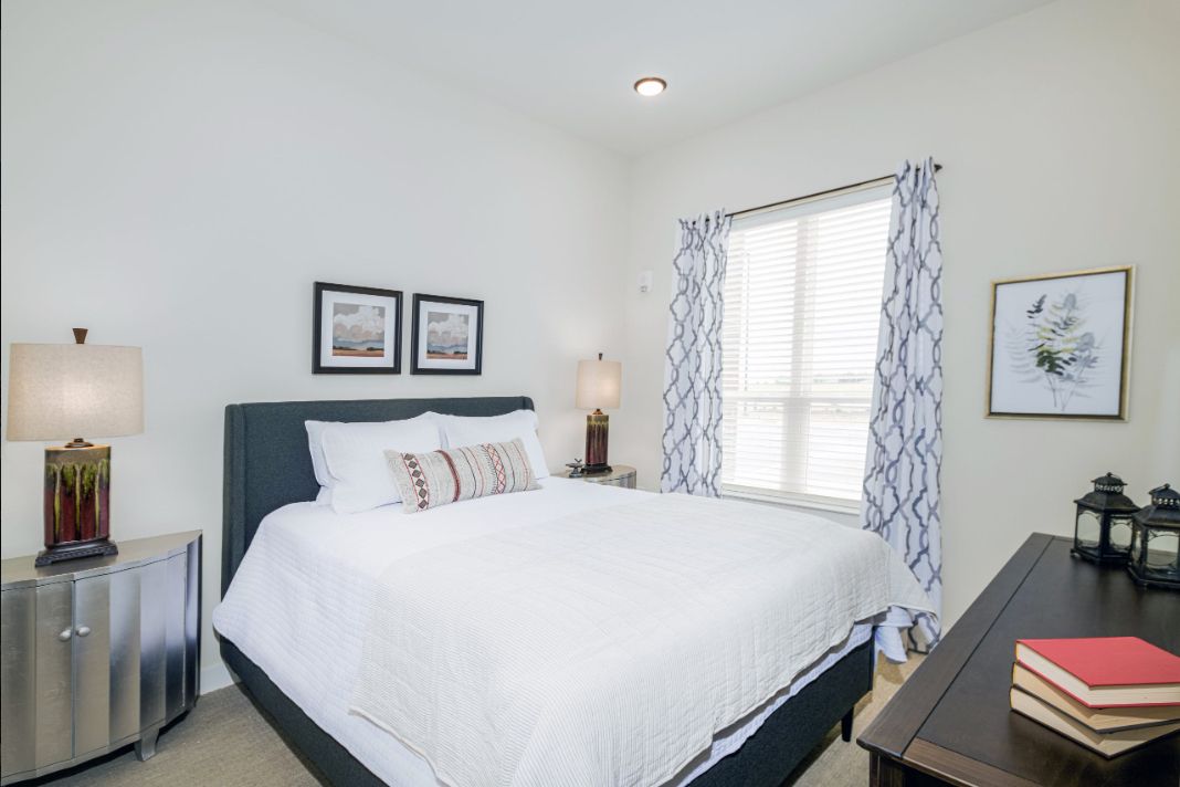 A modern bedroom with a white bedspread and stylish decor.