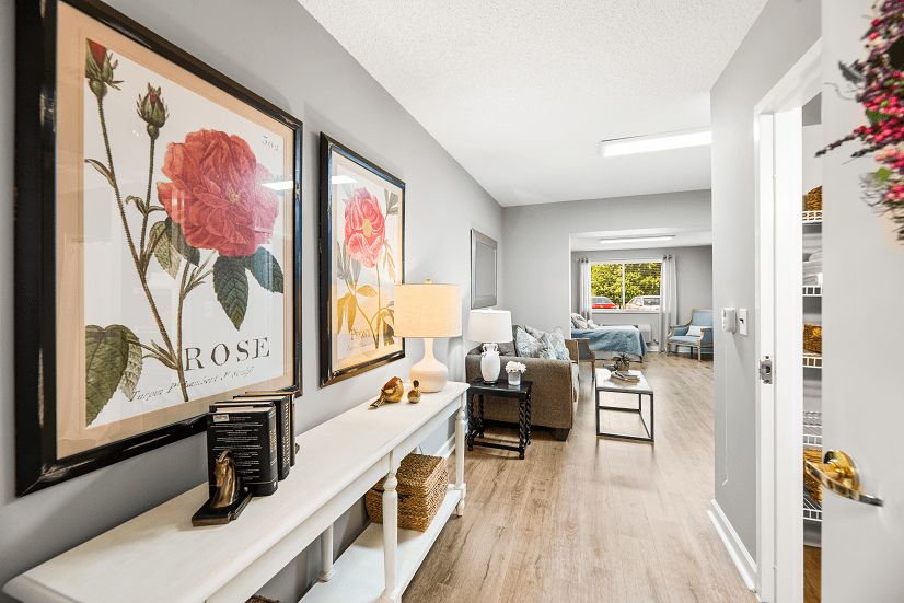 A modern hallway with floral artwork, a console table, and stylish furniture in a well-lit living space.
