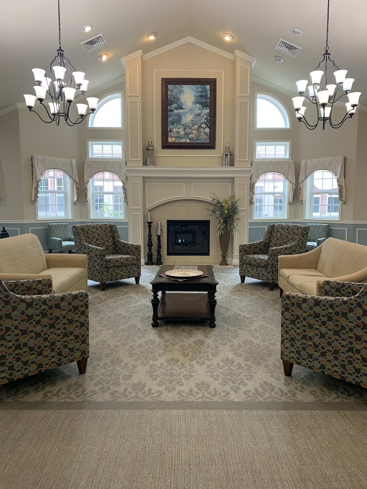 A spacious living room with a fireplace, comfortable seating, and elegant chandeliers.