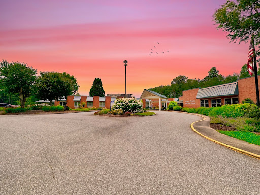 A serene view of a landscaped entrance at sunset, showcasing vibrant colors in the sky.