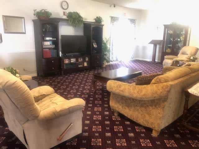 A cozy living room with plush sofas, a television, and a decorative carpet.